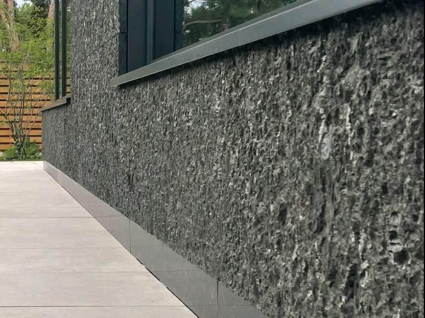Textured dark stone plinth on a façade with full-height glazing